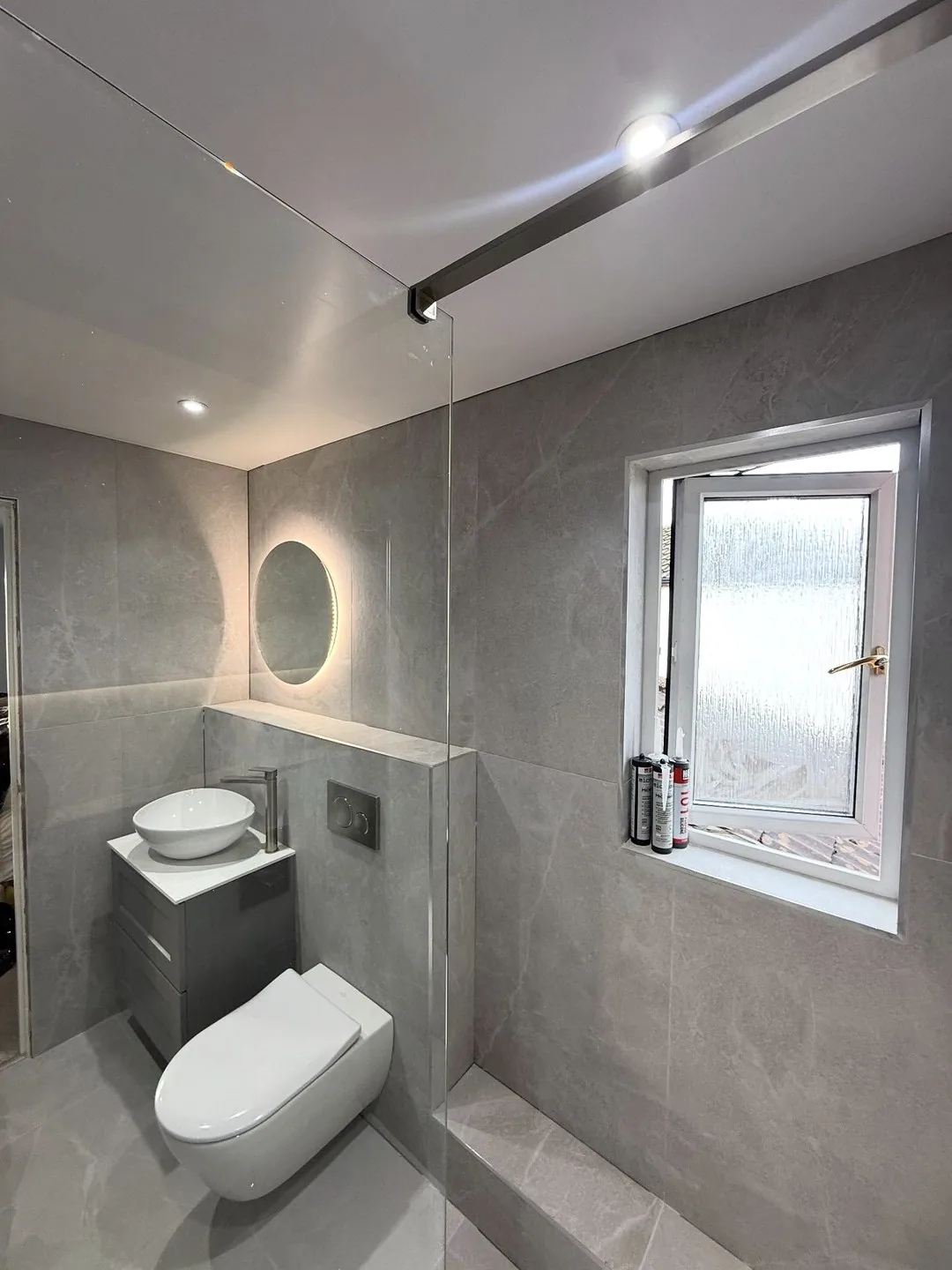 Stone-effect bathroom WC with lit mirror and window