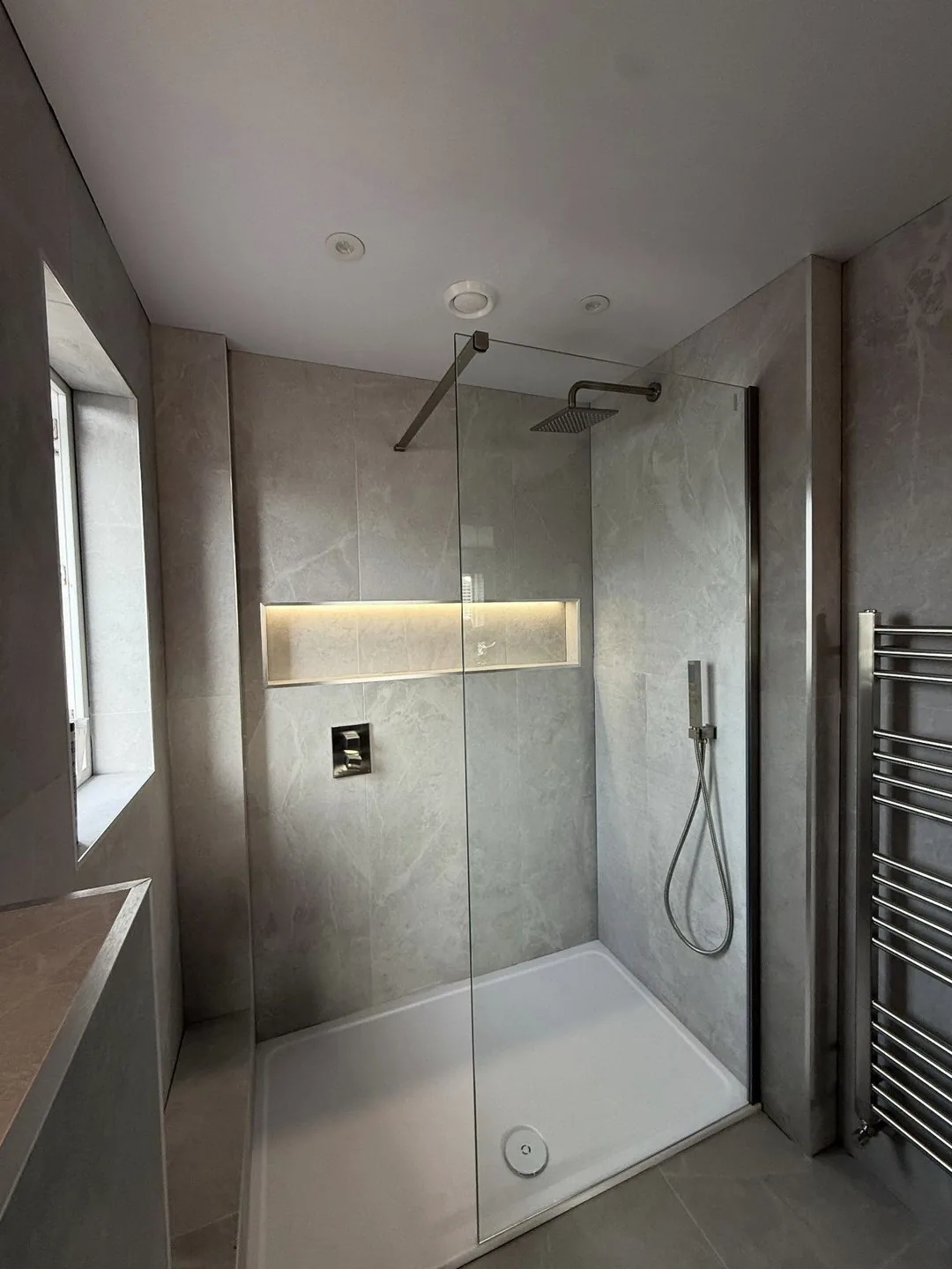 Walk-in shower with lit niche and heated towel rail