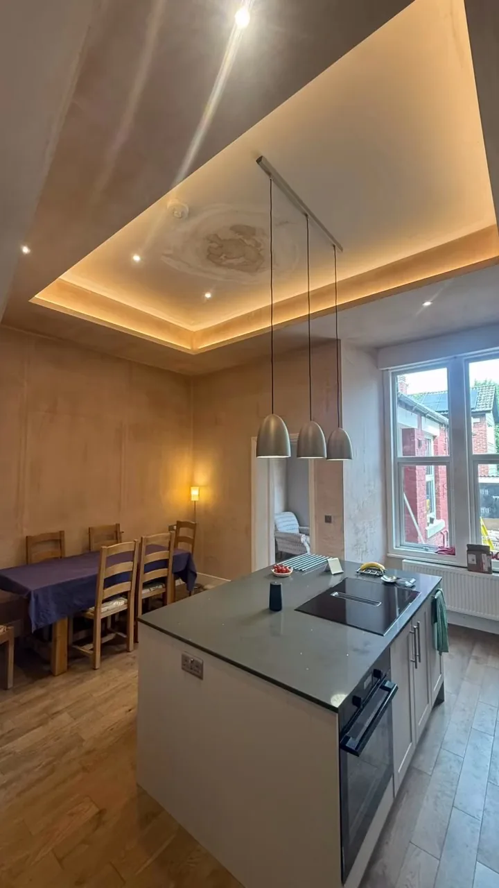 Finished kitchen island with pendant lights and concealed ceiling lighting