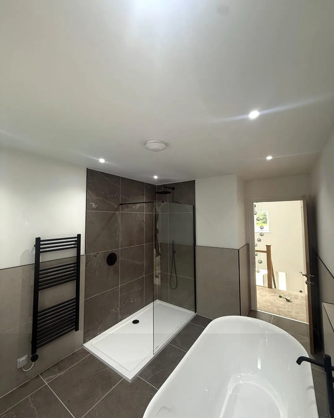 Main bathroom walk-in shower with recessed ceiling lights and heated towel rail