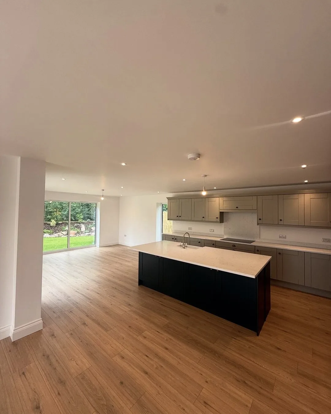 Open-plan new-build kitchen with island pendant and downlights