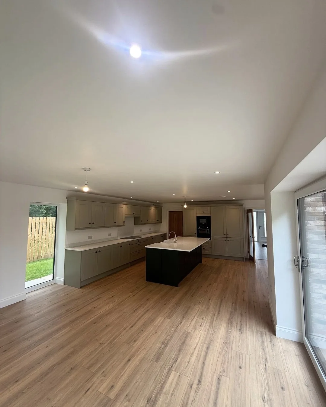 Completed new-build kitchen lighting seen from the garden doors