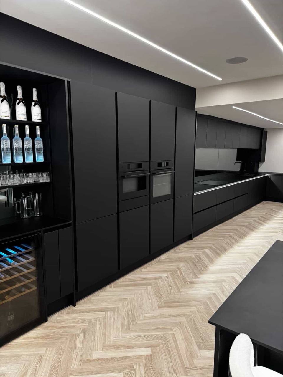 Matte-black kitchen units, ovens and illuminated worktop run